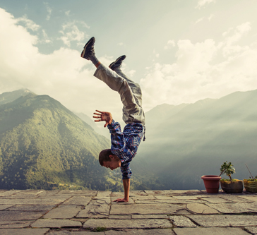 Man doing a hand stand at a mountaintop retreat, experiential event concept